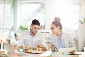 Young engineer showing sample of wood to colleague during discussion of its quality