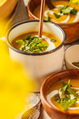 Autumn pumpkin soup puree with cream in cups, the autumn scenery. Healthy vegan food concept.