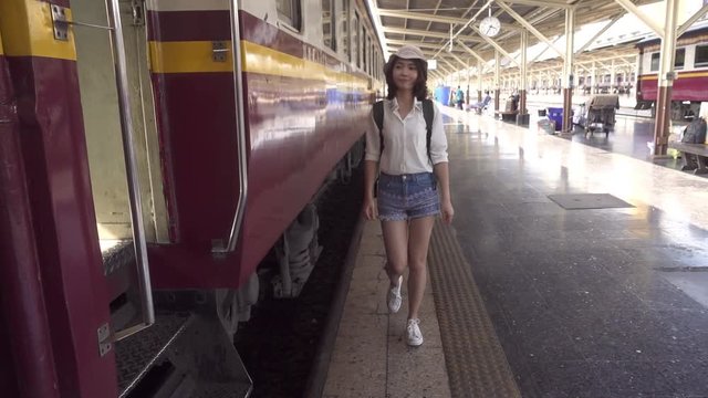 Slow motion - Happy Asian woman waiting the train at train station for travel in summer. Travel Thailand concept.