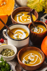 Autumn pumpkin soup puree with cream in cups, the autumn scenery. Healthy vegan food concept.