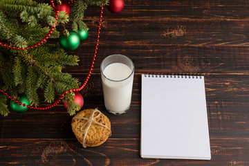 Milk, cookies and a wish list under the Christmas tree. The concept of the arrival of Santa Claus.