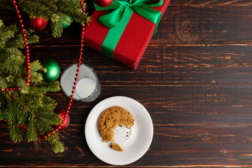 Empty glass of milk and crumb biscuits and a gift under the Christmas tree. The concept of the arrival of Santa Claus.
