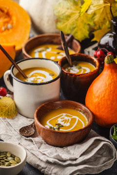 Autumn pumpkin soup puree with cream in cups, the autumn scenery. Healthy vegan food concept.