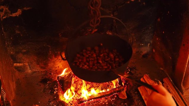 Cooking roasted chestnuts in the pan on fire in an autumn day