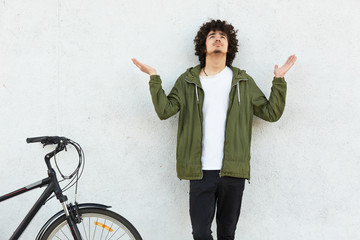 Oh God, help me please! Plesding male teenager spreads palms and raises head, prays for something...
