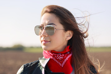 Rock style. Close up shot of dark haired thoughtful woman dressed in leather jacket, red bandana...
