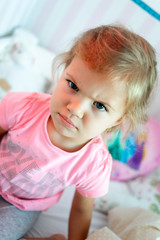 Fototapeta premium Angry little girl sitting on a bed.
