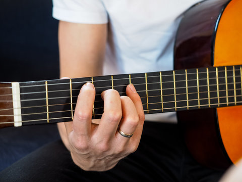 Male person playing acoustic guitar at closeup