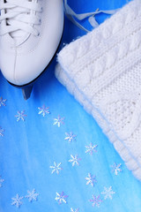 White figure skates and a knitted scarf against the blue background