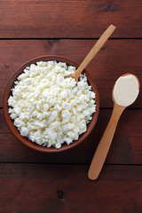 Cottage cheese. Cottage cheese and cream on wooden boards. Soft cheese in earthenware dish. Dairy products with wooden spoon. Sour cream in spoon. Copy space