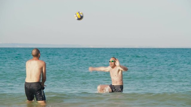 Guys play volleyball in the water. Volleyball on the beach.