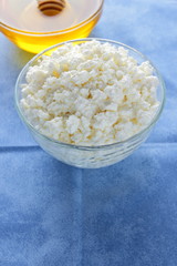 Cottage cheese. Cottage cheese and honey on blue napkin. Soft cheese in glassware. Dairy product for breakfast. Copy space