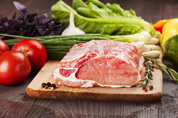 Raw pork for cooking and  barbecue on cutting board with vegetables.