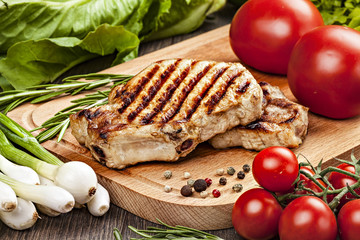Pork steak with vegetables, spices. Close-up on cutting board.