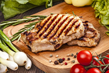 Pork steak with vegetables, spices. Close-up on cutting board.