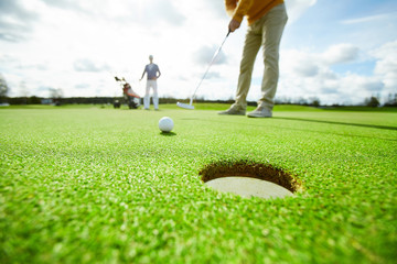 Einer der Golfspieler wird es während des Spiels direkt in das Loch im Rasen schlagen