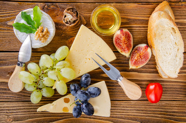 Cheese, fruit and honey. Tool for cheese. Wooden table. Top view.