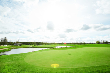 Beautiful panorama of vast green field with small pond or lake in rural environment