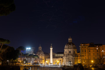 Night view of the old city in Rome. Blurry birds flying in the night sky - a long exposure.