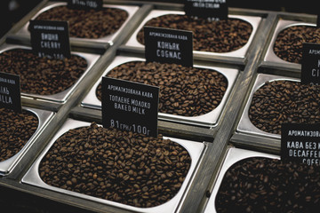 Big retro steel coffee boxes with black roasted beans flavored in different ways, including baked milk, cognak and other. Ukrainian translations above