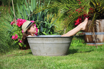 Ein Mädchen sitzt in einer verzinkten Badewanne