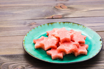 Pieces of watermelon in the form of stars on a ceramic plate on a wooden table