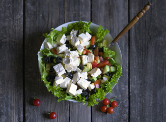 Plate with Fresh Greek salad on a wooden background
