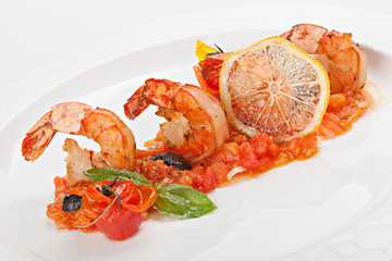 Close up of shrimps served with tomato sauces and slice of lemon.