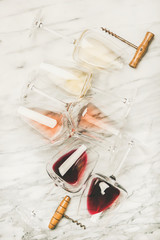 Flat-lay of red, rose and white wine in glasses and corkscrews over grey marble background, top view. Bojole nouveau, wine bar, winery, wine degustation concept © sonyakamoz