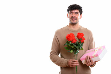 Thoughtful young happy Persian man smiling while holding red ros