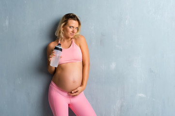 Fototapeta premium Blonde pregnant woman doing sport with a bottle of water