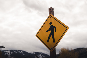 A crosswalk sign with clouds in the background. 