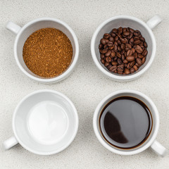 assortment of four white cups of coffee on a saucer grain, instant, brewed and an empty cup on the coffee table.