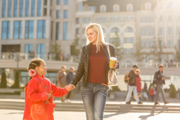 Young mother and daughter taking walk in city during sightseeing tour