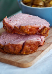 Frischer bayerischer Leberkäse und Breze aus dem Ofen mit Bratkartoffeln im Biergarten Wirtshaus zum Essen