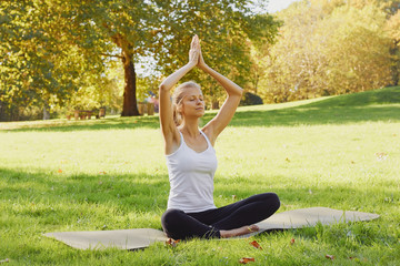 Girl meditates while practicing yoga outdoors in park