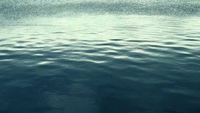 Marine picture. Slow motion blue sea water with a reflection of the sky on its surface of white volumetric clouds. Calm excitement on the sea surface on the sunset