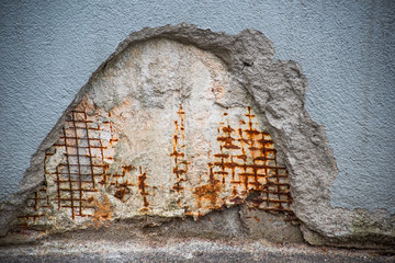 Fragment of a shattered wall with a reinforced metal mesh