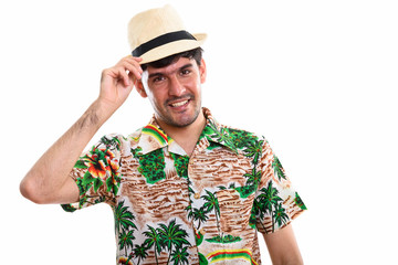 Studio shot of young happy Persian man smiling while holding hat