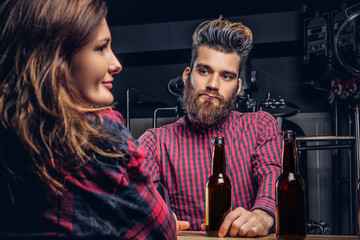 Bearded male and his girlfriend enjoying craft beer during dating at indie brewery.