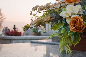 Floral decoration on the grave with a cementary in the background