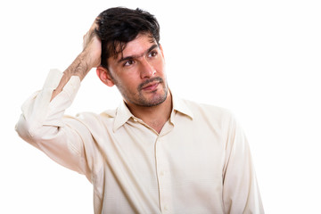 Studio shot of young Persian businessman thinking while brushing