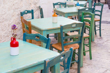 Fototapeta na wymiar Green wooden outdoor tables and chairs of an italian restaurant