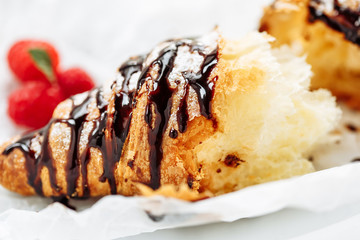 Tasty croissant with cream and topping on plate. Close-up shot with tasty fresh texture of liquid chocolate
