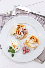 Crepes Pancakes with fruit jam and ice cream. Top view on white wooden table