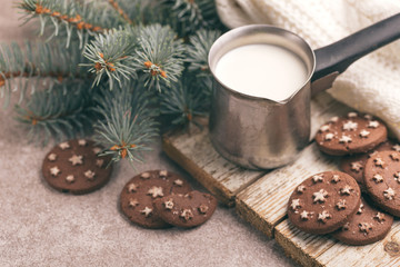 Chocolate cookies with jar of hot milk on the old wooden cutting board.