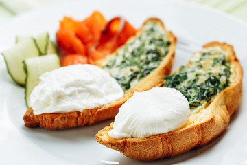 Whole wheat toasted croissant with arugula and poached egg, smoked salmon. Table arrengement side view copy space