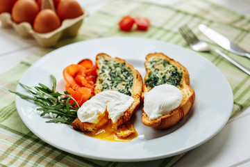 Whole wheat toasted croissant with arugula and poached egg, smoked salmon. Table arrengement top view copy space