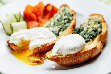 Whole wheat toasted croissant with arugula and poached egg, smoked salmon. Table arrengement side close-up view copy space