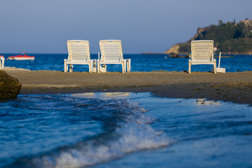 White, plastic sunbeds at golden hour on sandy beach of Zakynthos, Greece